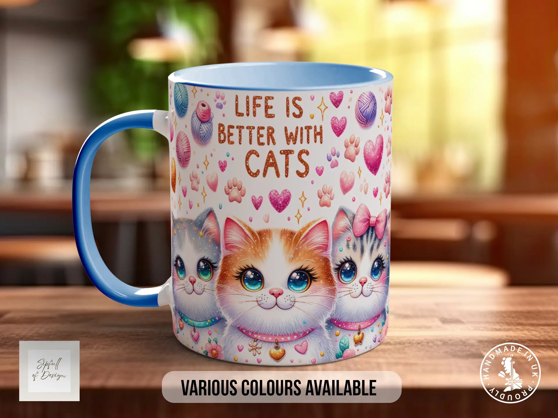 A mug with a cat design, featuring three cats with blue eyes and pink bows. The mug has a blue handle and is placed on a wooden surface.