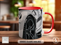 A red and white mug with a graphic of a car on it, placed on a wooden surface.