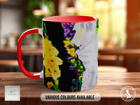 A red and black mug with a colorful floral design on it, sitting on a wooden surface.