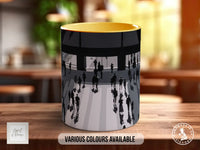 A ceramic mug with a black and white illustration of people walking on a street, with a yellow interior.