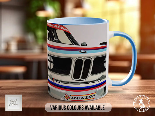 A blue and white mug with a graphic of a car on it, placed on a wooden surface.