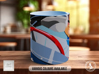 A colorful mug with abstract designs on it, placed on a wooden surface.