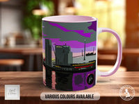 A mug with a colorful illustration of a cityscape, featuring a mix of purple, gray, and black tones.