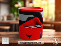 A red mug with a black and white abstract design on it, sitting on a wooden surface.
