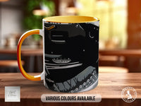 A black and orange mug with a graphic design on it, placed on a wooden surface.