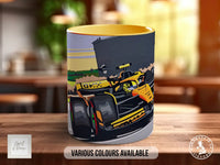A ceramic mug with a colorful illustration of a racing car on it, placed on a wooden surface.