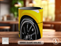 A yellow and black mug with a graphic of a wheel on it, sitting on a wooden surface.