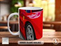 A white ceramic mug with a red and yellow car design on it, placed on a wooden surface.