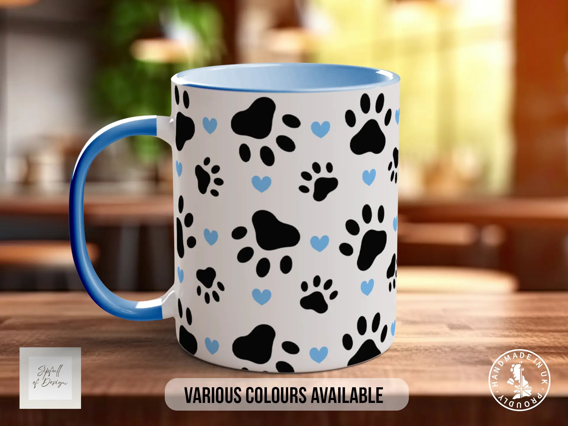 A white mug with a blue handle, featuring a pattern of black paw prints and blue hearts on a wooden surface.