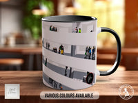 A mug with a printed design of people on it, sitting on a table.