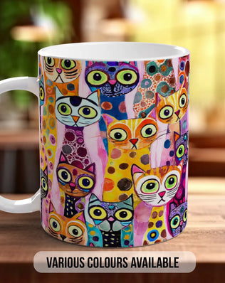 A colorful mug with a playful cat design printed on it, sitting on a wooden surface.