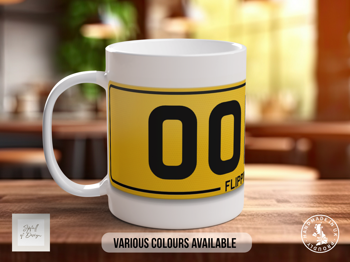 A white mug with a yellow and black design featuring the number "00" and the word "FLIPPER" printed on it, sitting on a wooden surface.