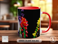 A red and black mug with a colorful floral design on it, placed on a wooden surface.