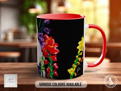A red and black mug with a colorful floral design on it, placed on a wooden surface.