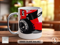A white mug with a graphic design featuring a red and black car on a wooden table.