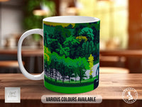 A white mug with a colorful landscape design printed on it, placed on a wooden surface.