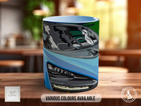 A ceramic mug with a colorful abstract design, featuring various shades of blue, green, and gray.