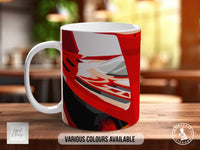 A white mug with a colorful abstract design on it, placed on a wooden surface.