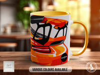 A colorful mug with an abstract design featuring a car or vehicle, placed on a wooden surface.