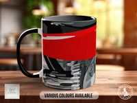 A black and red mug with a graphic design on it, sitting on a wooden surface.