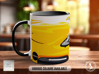 A black and yellow mug with a stylized design on it, placed on a wooden surface.