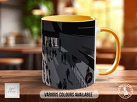 A yellow and black mug with a graphic design depicting a crowd of people on a street.