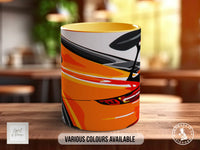A colorful mug with a graphic design of a car on it, sitting on a wooden surface.