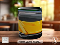 A black and yellow mug with a graphic design on it, placed on a wooden surface.
