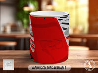 A red mug with a graphic design on it, sitting on a wooden surface.