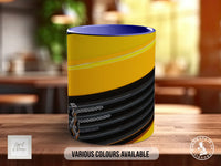 A colorful mug with a yellow and black striped pattern, placed on a wooden surface.