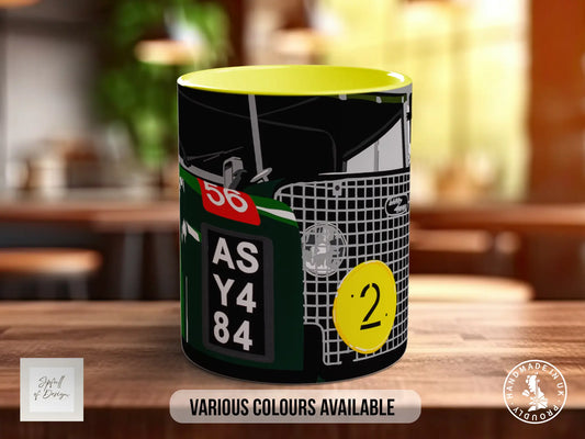 A mug with a black and yellow design featuring a car and the number "56" and "2" on it, placed on a wooden surface.