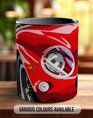 A red car mug with a graphic design on it, sitting on a wooden surface.