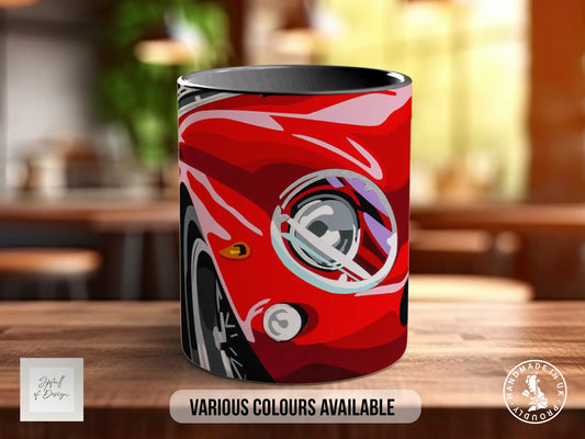 A red car mug with a graphic design on it, sitting on a wooden surface.