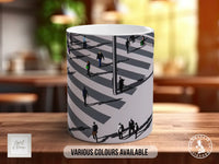 A white mug with a black and gray zebra crossing design printed on it, sitting on a wooden table.