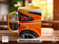 A colorful coffee mug with an abstract design featuring orange, black, and white colors.