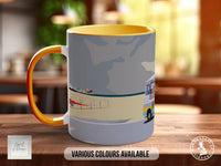 A mug with a colorful design featuring a boat and a vehicle, along with the text "Various Colours Available" and "Handmade in UK".
