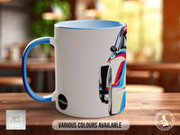 A white mug with a blue handle, featuring an image of a racing car on the side.