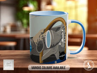 A blue and white mug with an illustration of a vehicle on it, placed on a wooden surface.