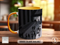 A mug with a black and white illustration of people walking up a staircase on a wooden surface.