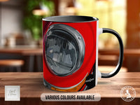 A red mug with a black handle, featuring a graphic of a car headlight on the side.