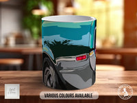 A ceramic mug with a colorful design depicting a car, placed on a wooden surface.