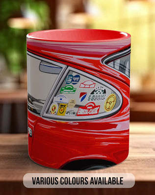 A red mug with a car decal on it, sitting on a wooden surface.