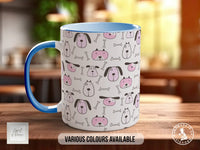 A white mug with a blue handle, featuring a repeating pattern of pink and black dog faces and bones on its surface.