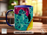 A colorful mug with a vibrant design featuring a flamingo and a tennis ball, sitting on a wooden surface.