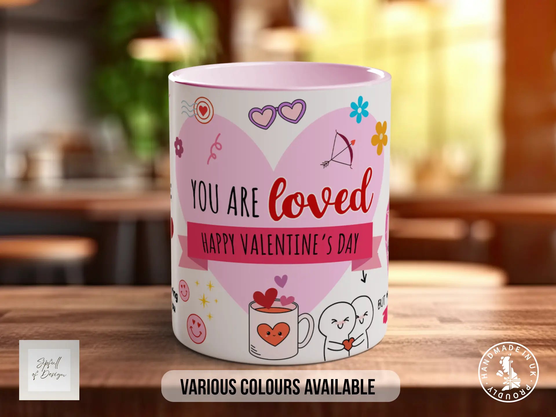 A pink and white mug with a heart-shaped design and various Valentine's Day-themed illustrations, along with the text "YOU ARE LOVED" and "HAPPY VALENTINE'S DAY".