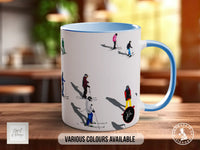 A white mug with a blue handle, featuring a design of people skiing on a snowy slope.