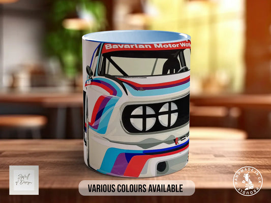 A colorful mug featuring a racing car design, with the text "Bavarian Motor Works" and "Various Colours Available" printed on it.