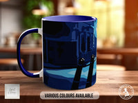 A blue and white mug with an illustration of a cityscape on it, sitting on a wooden surface.