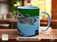 A blue and gray mug with an illustration of a car on it, placed on a wooden surface.