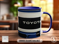 A blue and white mug with the word "TOYOTA" printed on it, sitting on a wooden surface.